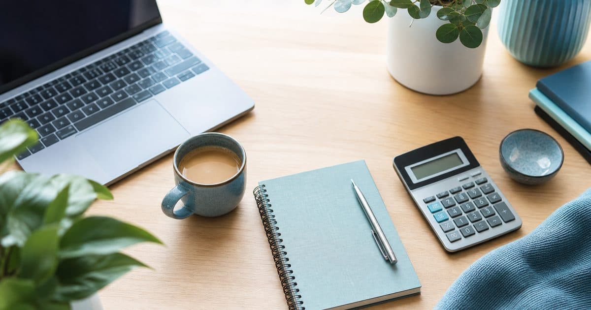 Desk with a laptop, calculator and notebook representing CRM cost planning